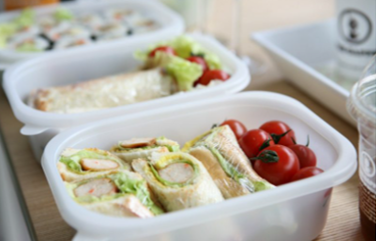 a row of plastic boxes containing sandwiches and salad