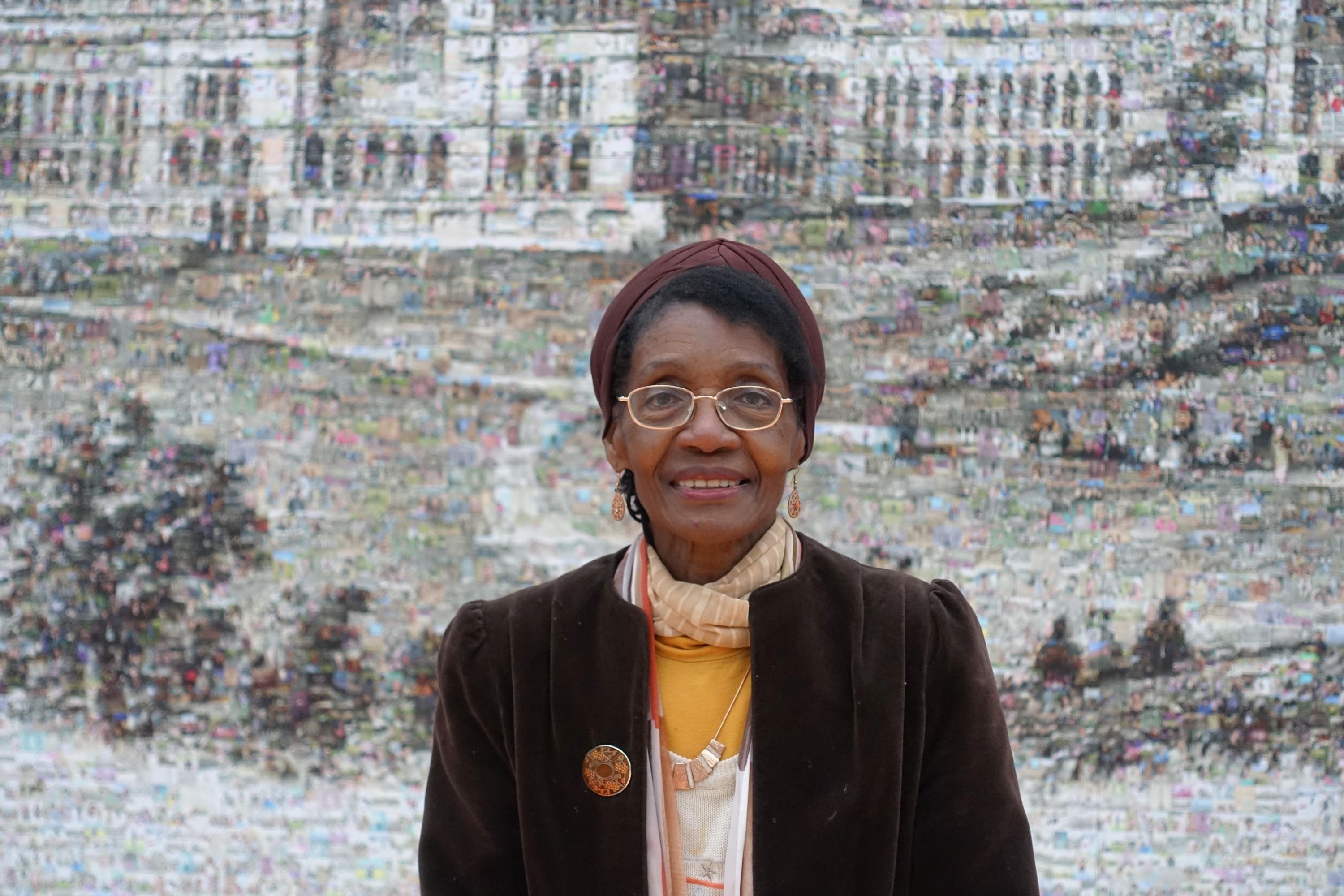 Person smiling looking straight into camera in front of a black and white mural