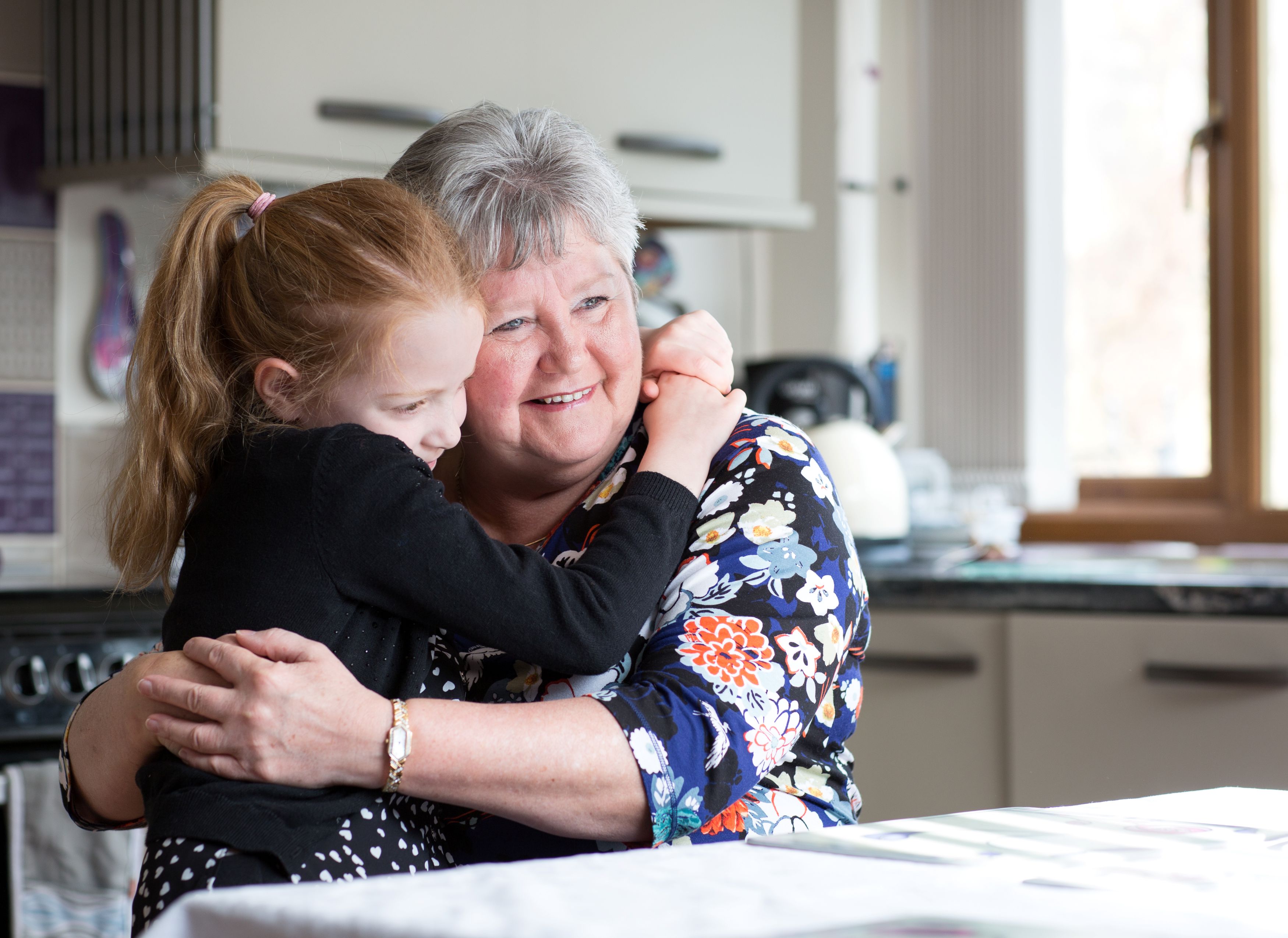Grandmother and grandchild hugging in kitchen