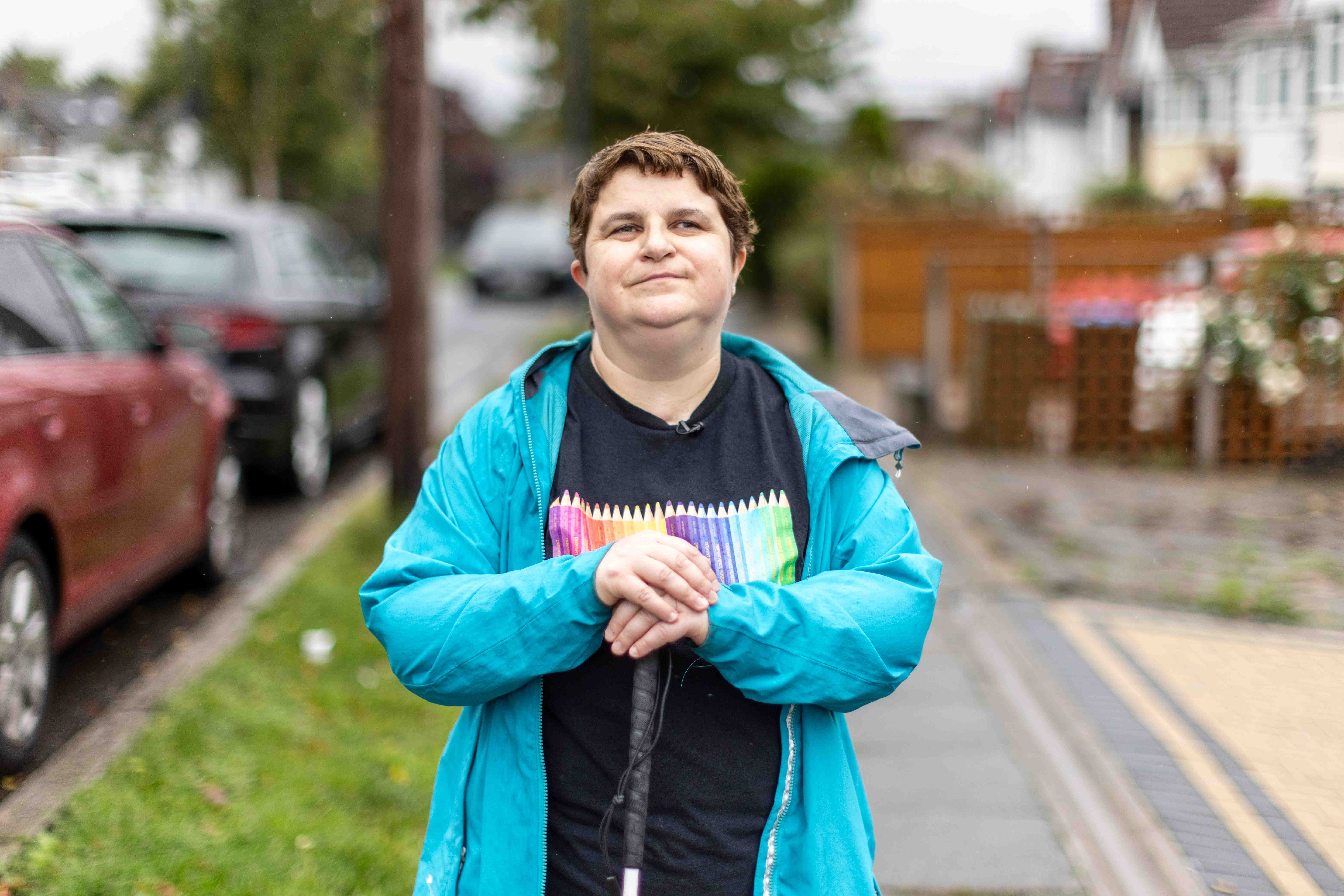 Charmaine stood in her street on the pavement with her hands rest on her cane