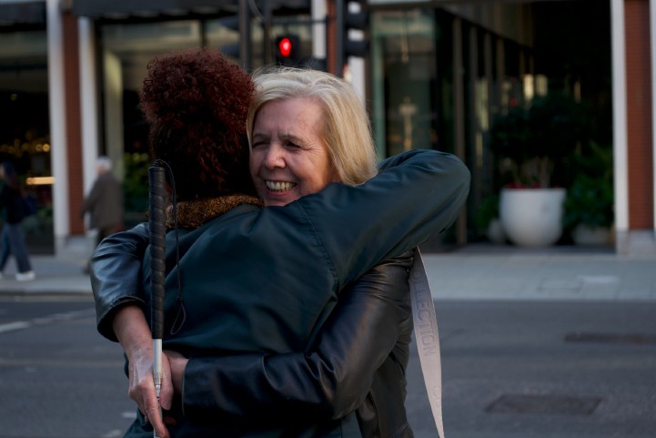 Heather smiles as she is hugged by a friend