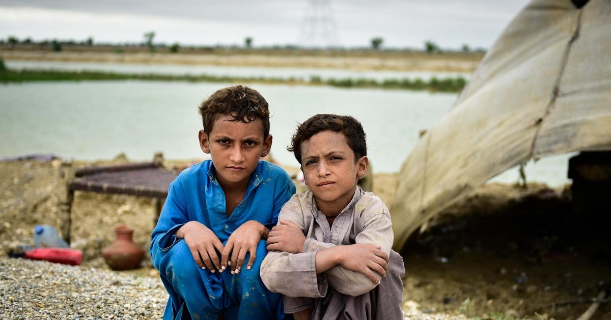 Two young boys sit together on the ground after being displaced from their village due to flash floods caused by abnormally heavy monsoon rains in Pakistan in August 2022.