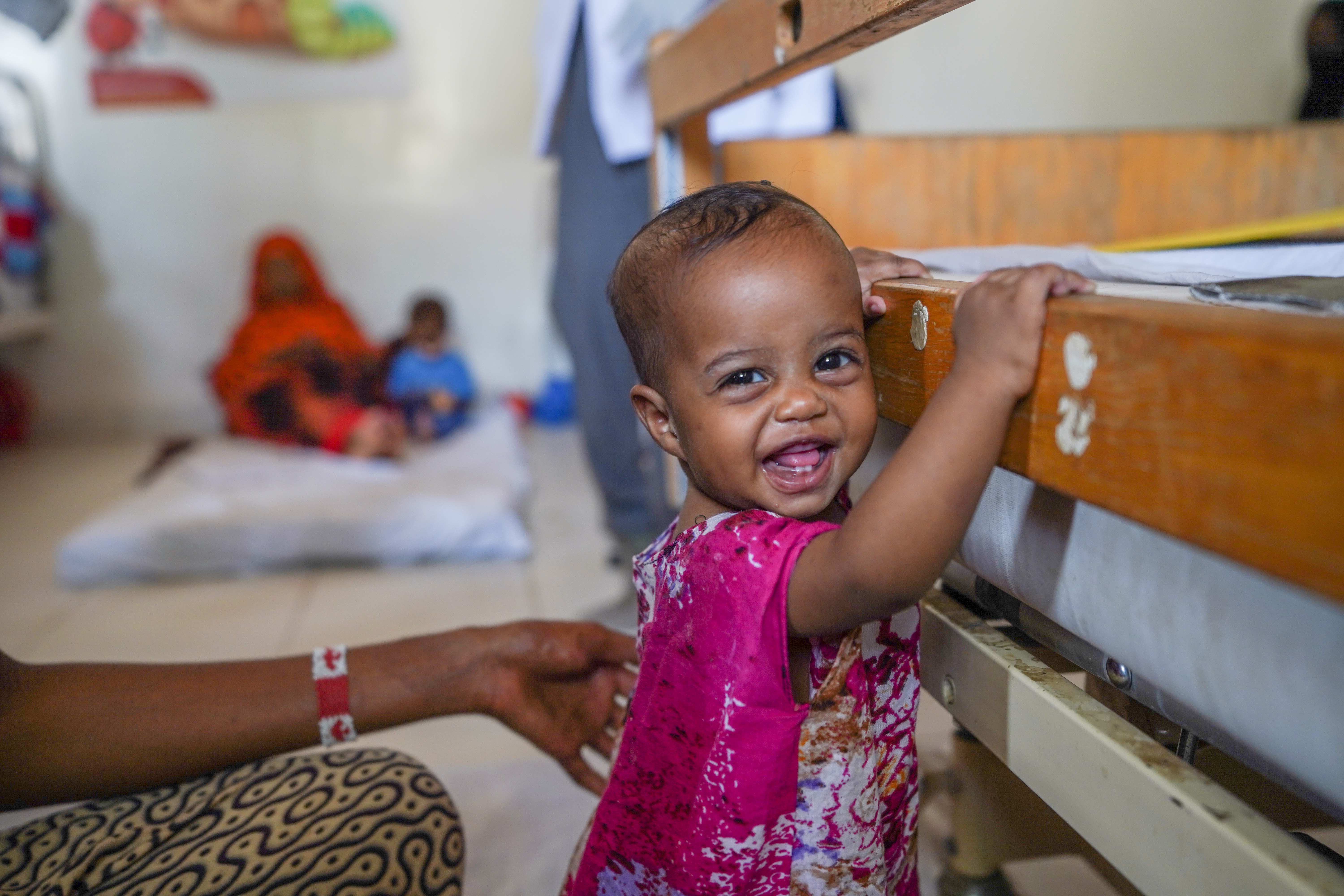 One year old girl standing and smiling at the camera. 