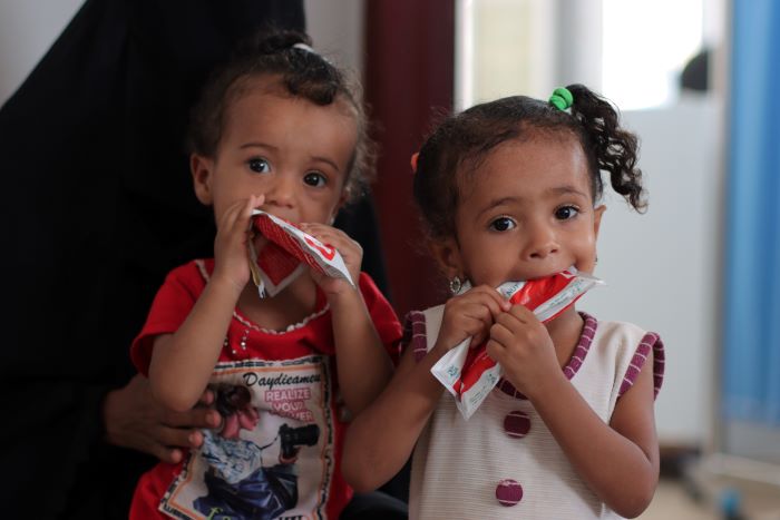 Deux jeunes filles, âgées de 3 et 1 ans, confrontées à la malnutrition, sont photographiées en train de manger des aliments thérapeutiques prêts à manger.