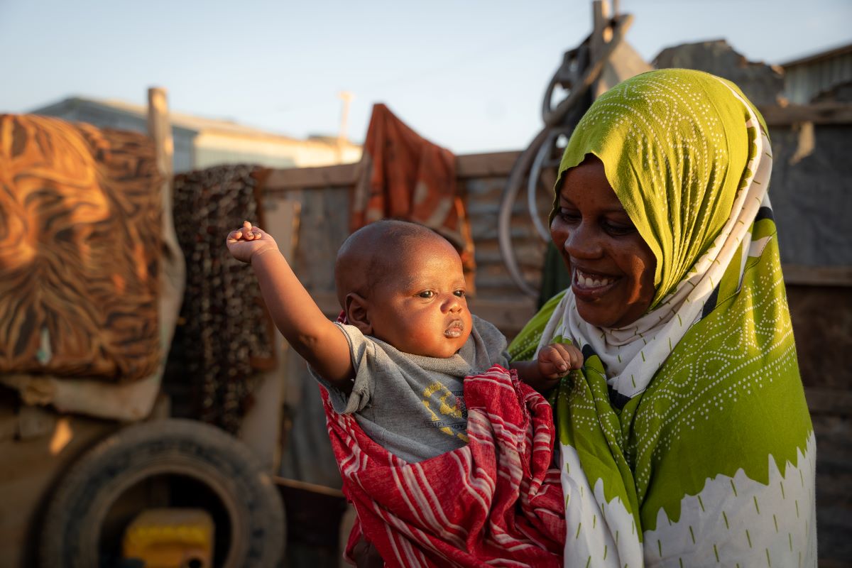 Mother holds her smiling 1-month-old son at their home in the Jawle camp for internally displaced people (IDPs) in Garowe.