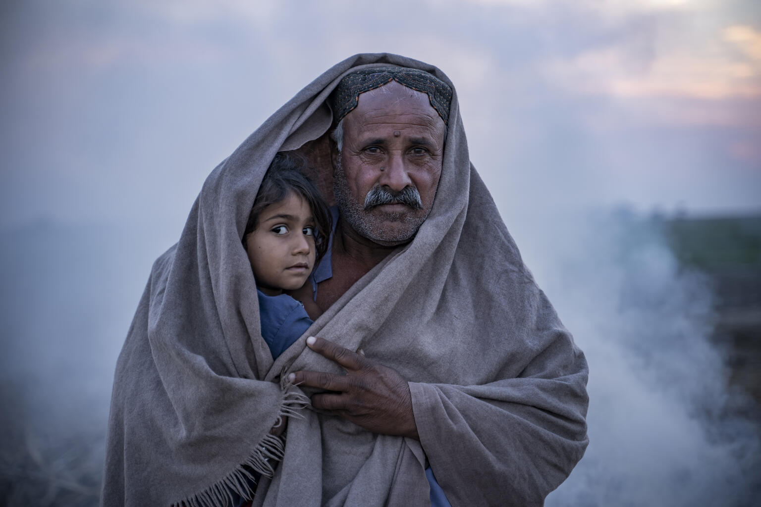 A man and a child wrapped in a blanket.