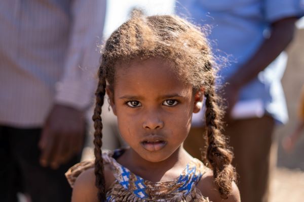 Une jeune fille se tient dans un centre de distribution soutenu par l’UNICEF à Kassala, au Soudan, pour y recevoir des moustiquaires de lit.