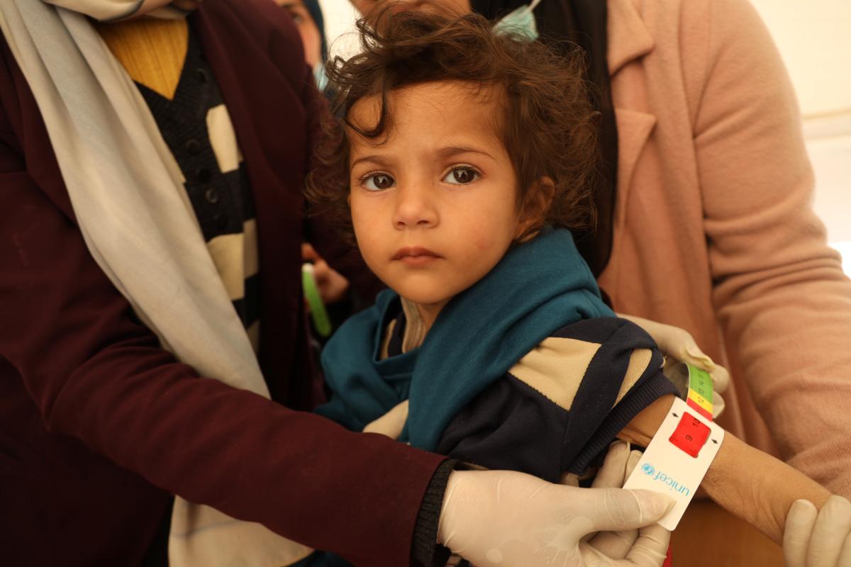Portrait rapproché d’une enfant à qui l’on mesure la circonférence de la partie supérieure du bras à l’aide d’un ruban millimétré de l’UNICEF qui indique une malnutrition aiguë sévère.