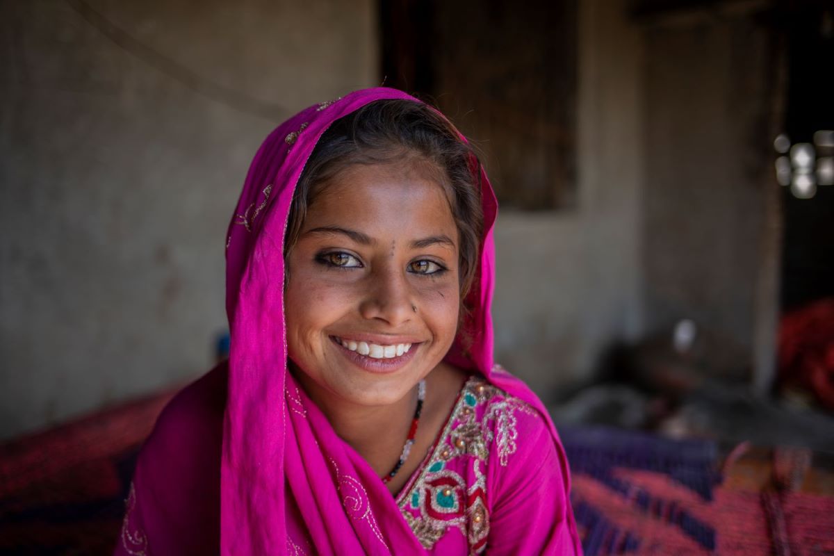 Portrait en gros plan d’une fille souriant à l’objectif et portant un foulard violet.