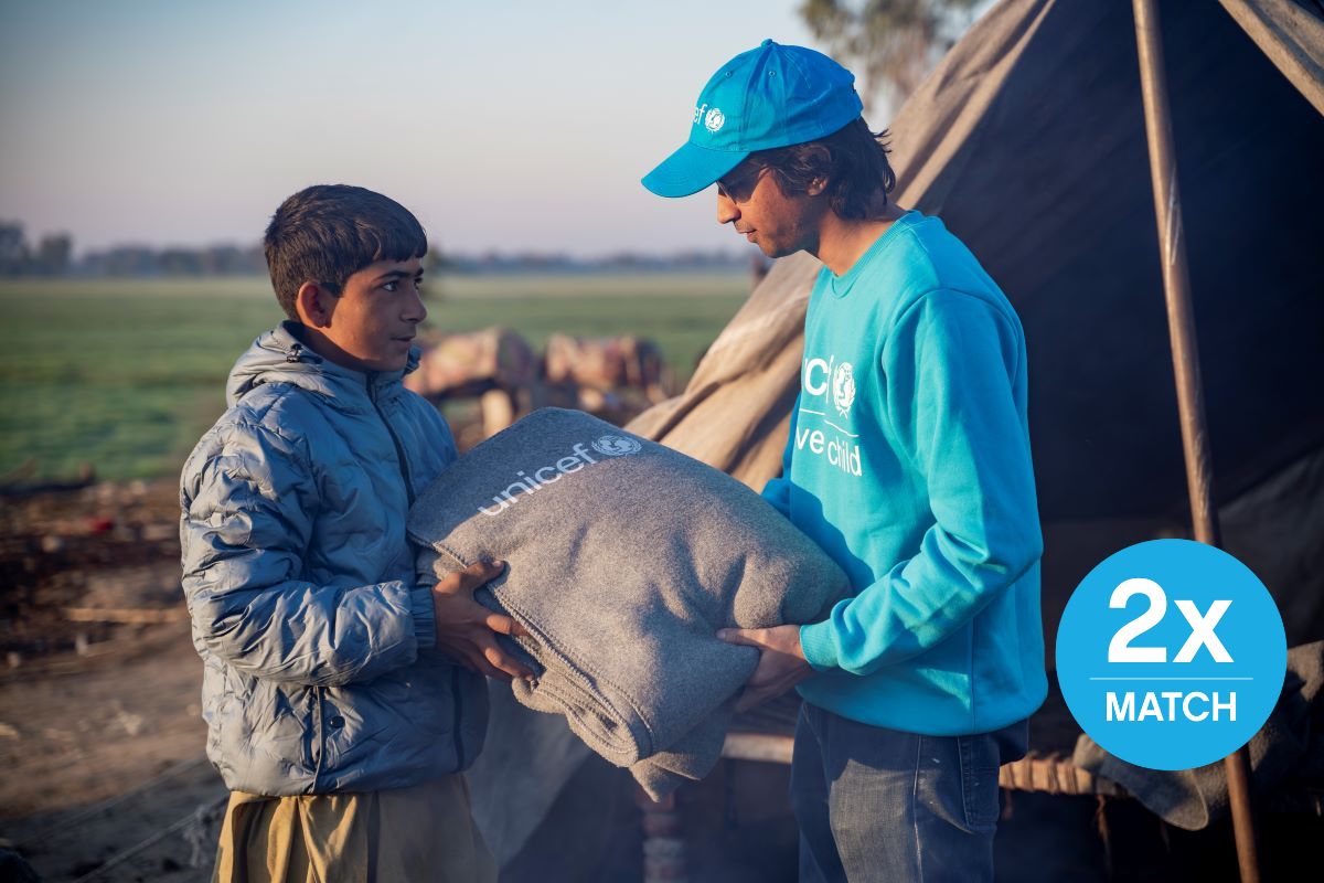 In Pakistan, a UNICEF worker gives a blanket to young boy.