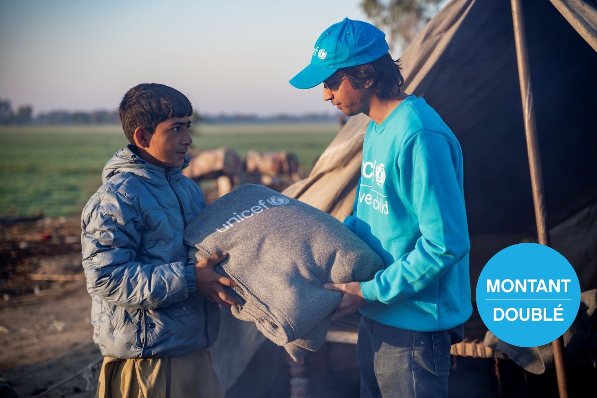 Au Pakistan, un employé de l’UNICEF donne une couverture à un jeune garçon.