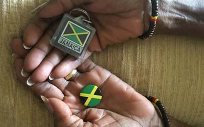Black hands holding a badge and keyring with Jamaican flag on them