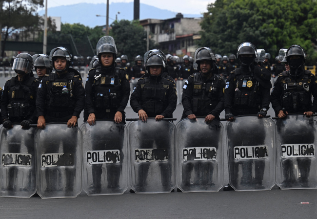 Riot police stand guard as demonstrators block a road on October 10 during a protest demanding the resignation of Attorney General Consuelo Porras, accused of persecution against President-elect Bernardo Arevalo.