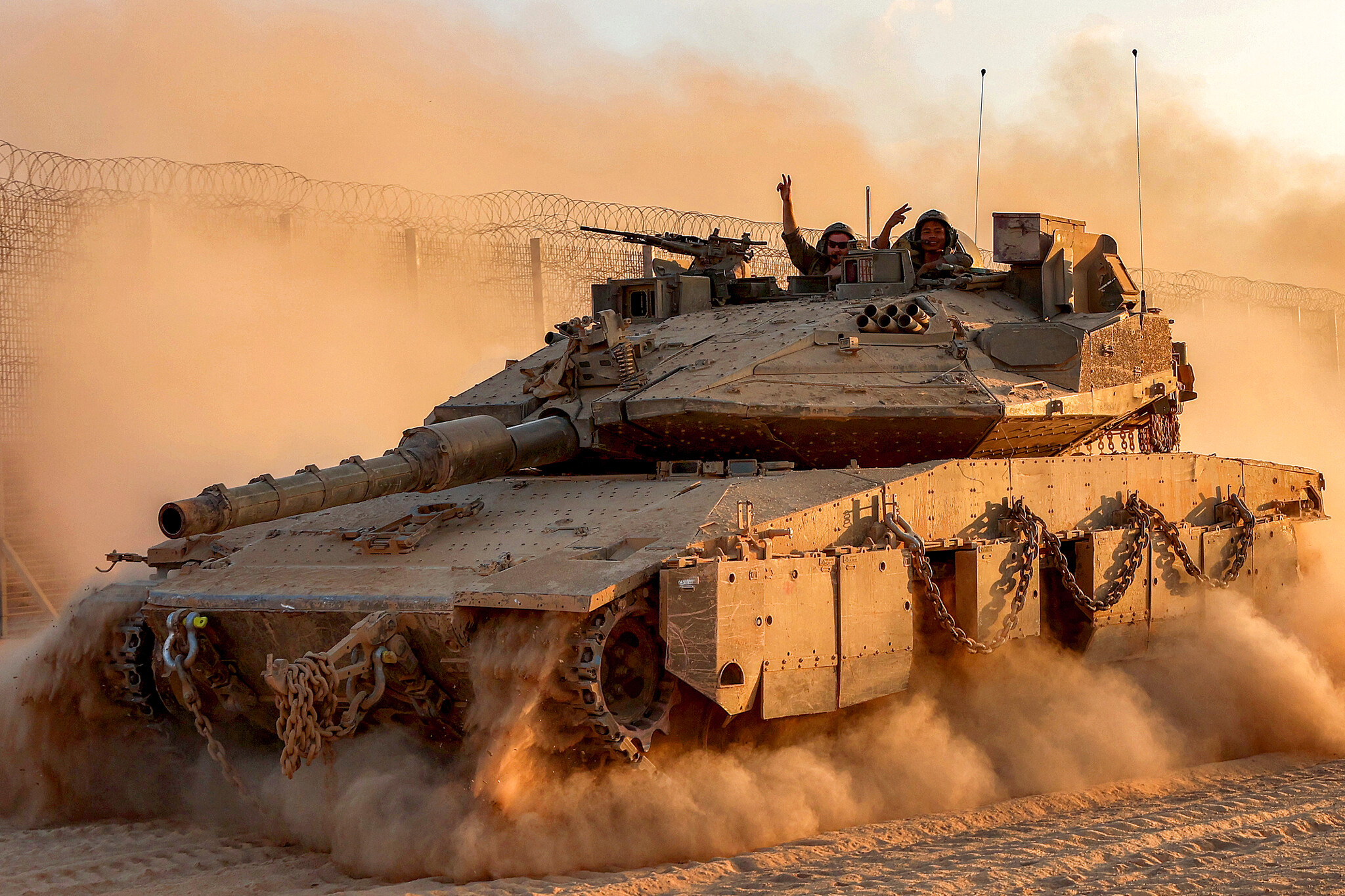 Israeli army soldiers gesture from the turret of a Merkava main battle tank moving at a position along the border fence with the Gaza Strip in southern Israel on September 12, 2025.