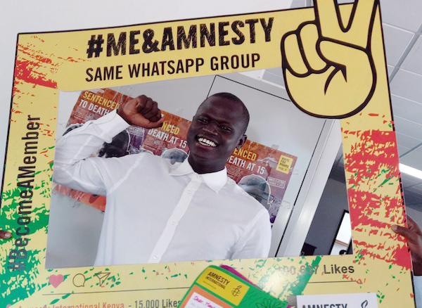Man standing behind a Me & Amnesty, Become a Member sign