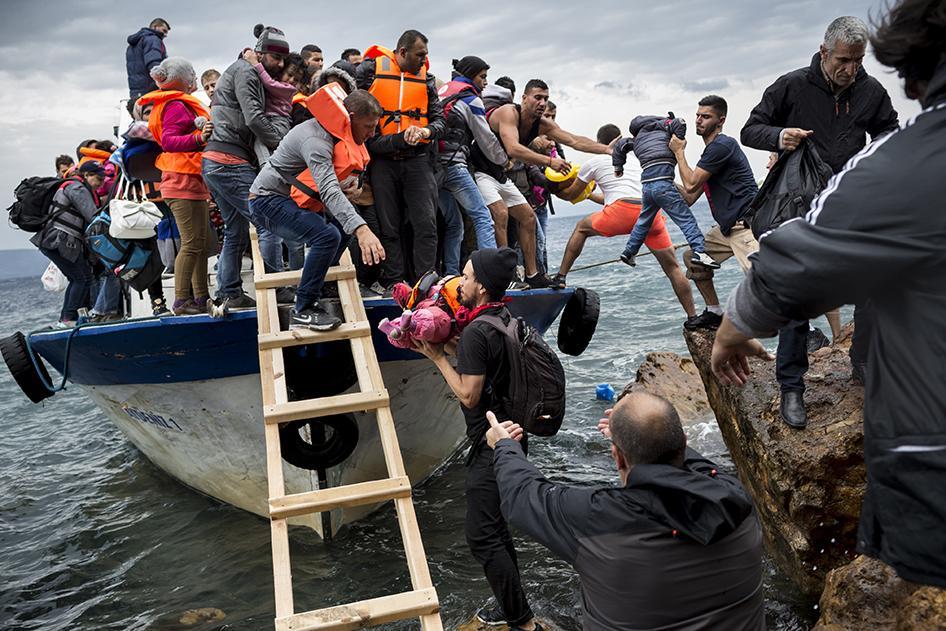 Asylum seekers and migrants descend from a large fishing vessel used to transport them from Turkey to the Greek island of Lesbos. October 11, 2015.  © 2015 Zalmaï for Human Rights Watch