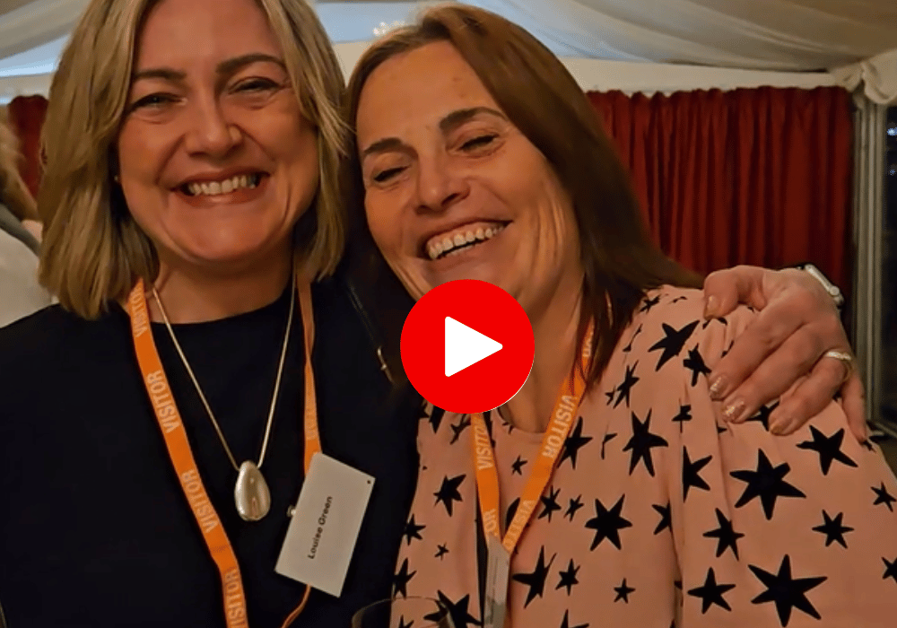 Two sisters hugging and smiling, with a play button overlaid to indicate that it's a video