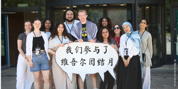 Amnesty UK’s Anti-Racism Network holding up a sign, reading ‘We’ve Joined Uyghur Solidarity Month’ at the AGM event ‘Amplify’. © Marie-Anne Ventura