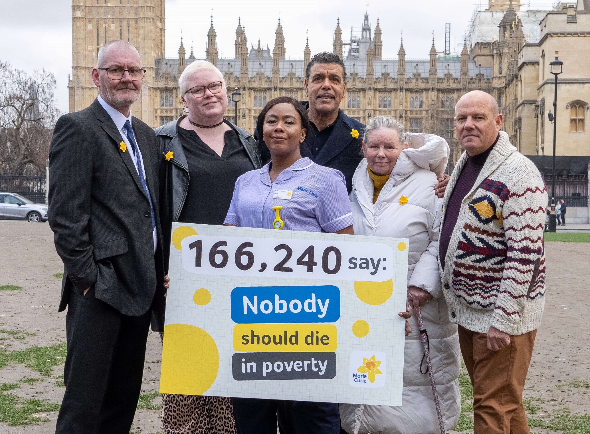 Campaigners and a Marie Curie nurse hold a sign that says 116,240 say: nobody should die in poverty. The Houses of Parliament are behind them.