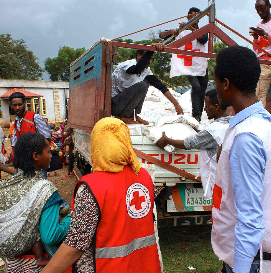 Red Cross staff and volunteers unload supplies from a truck.