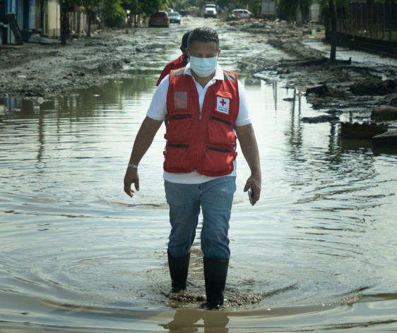Une personne travaillant pour la Croix-Rouge se déplace dans une rue inondée au Honduras.