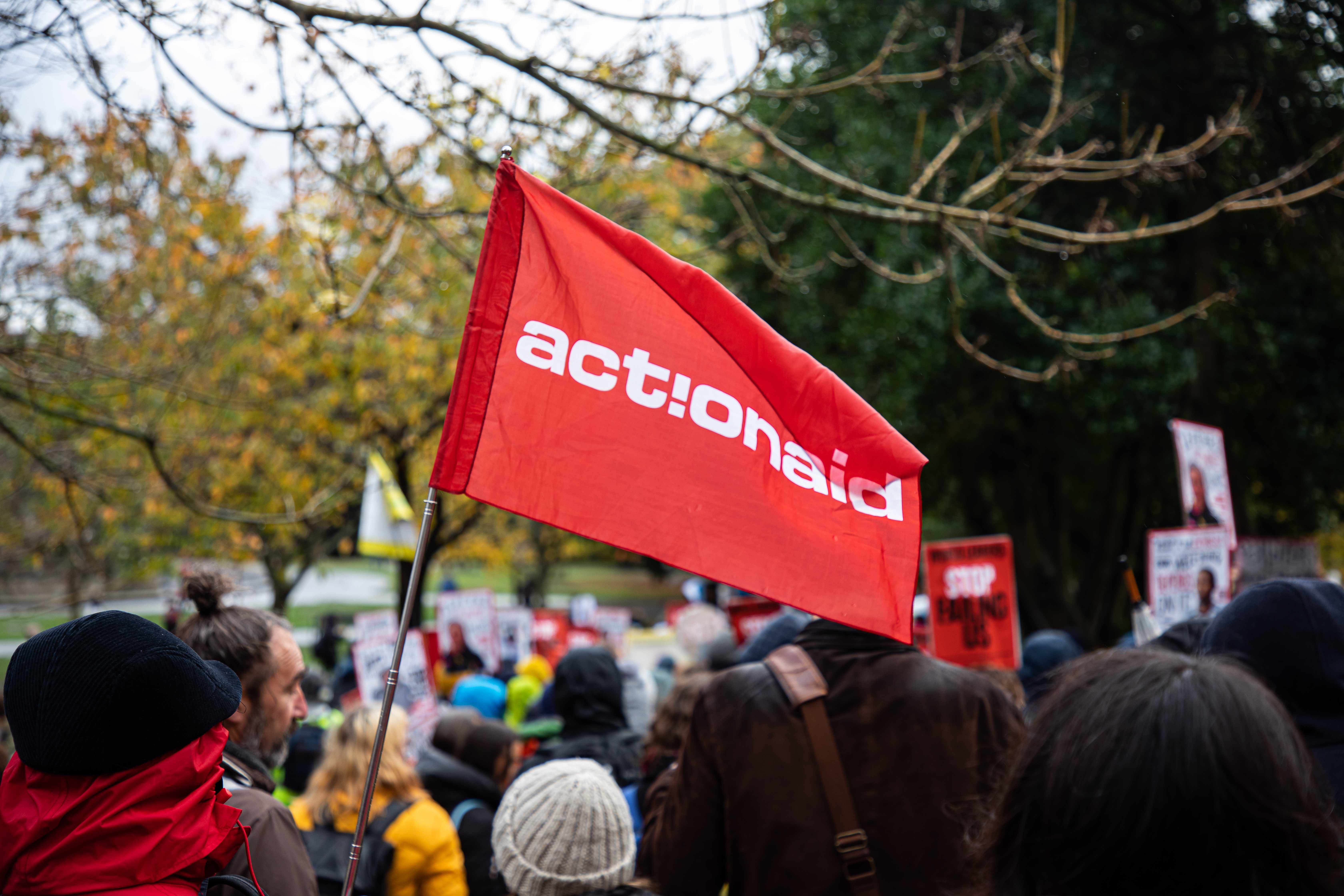 Photo of a red flag with the text "ActionAid" at the COP26 climate march in Glasgow.
