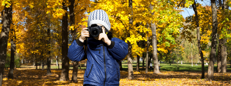 person taking photos in fall trees