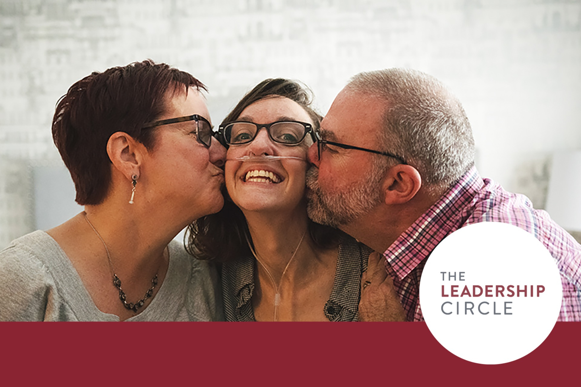 A mother and father kissing their daughter on the cheek.