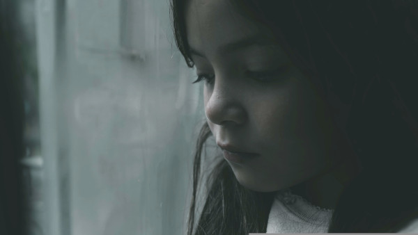 Photo of a girl staring sadly out of a window