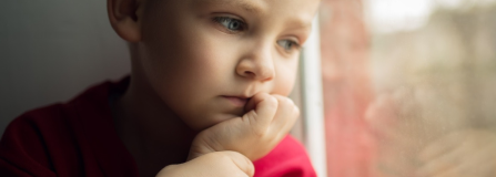 boy staring sadly out of window