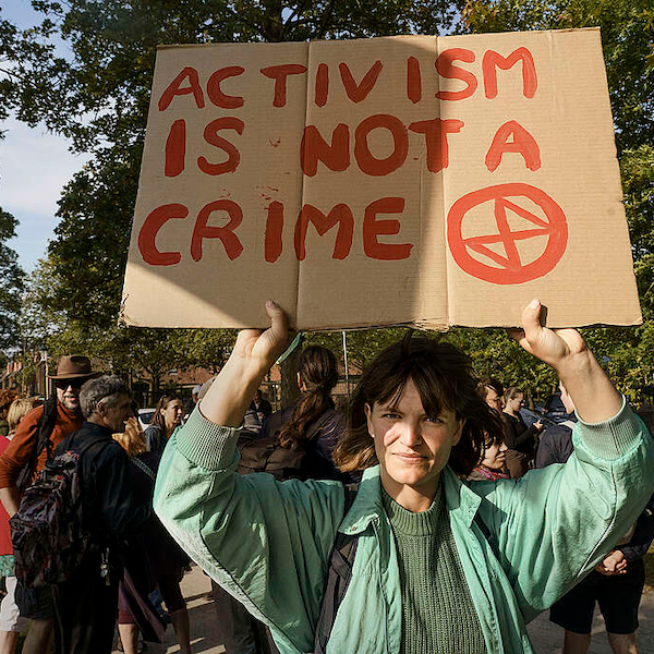 Een activist met een spandoek waarop staat: