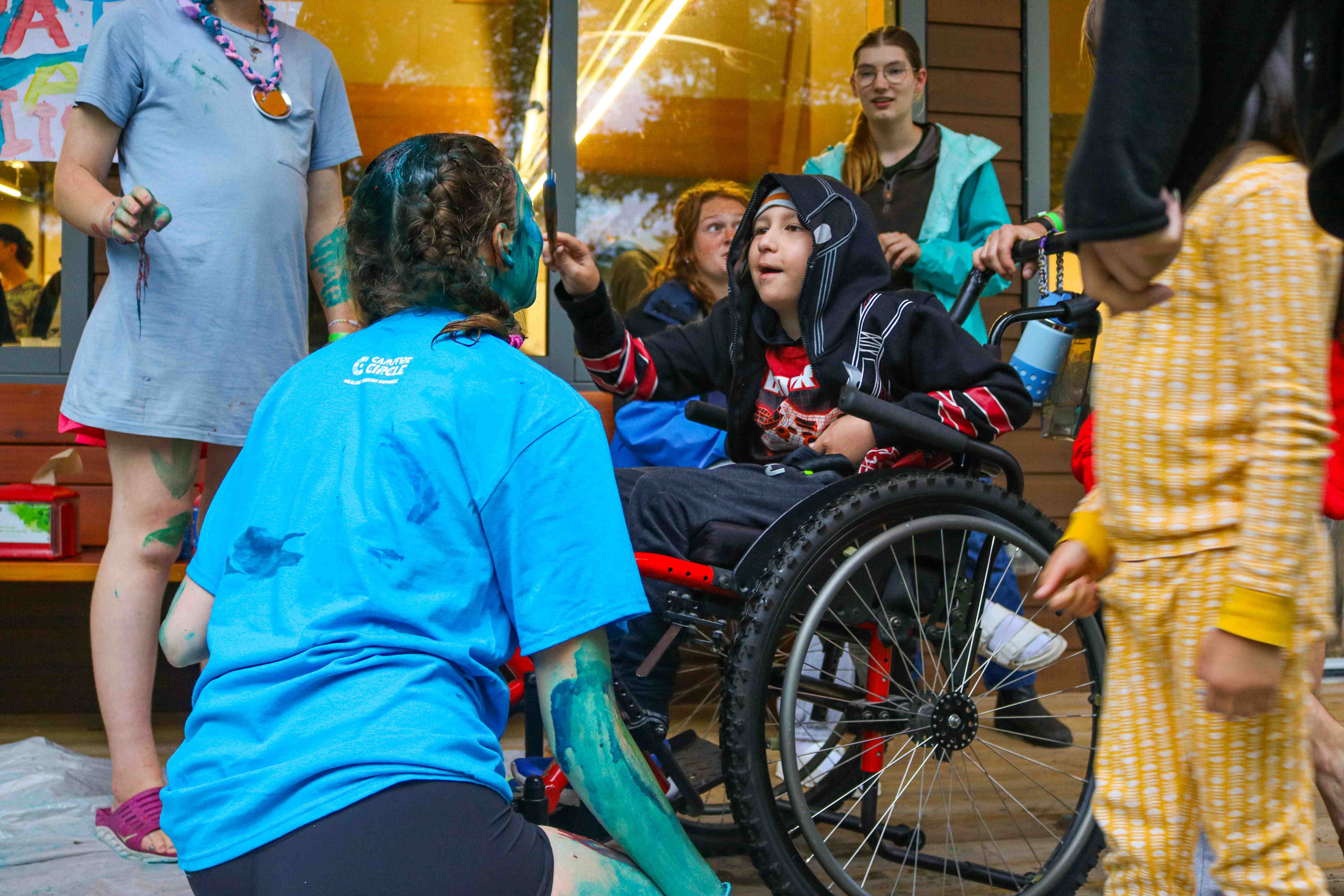 camper in a wheelchair painting a counsellor's face