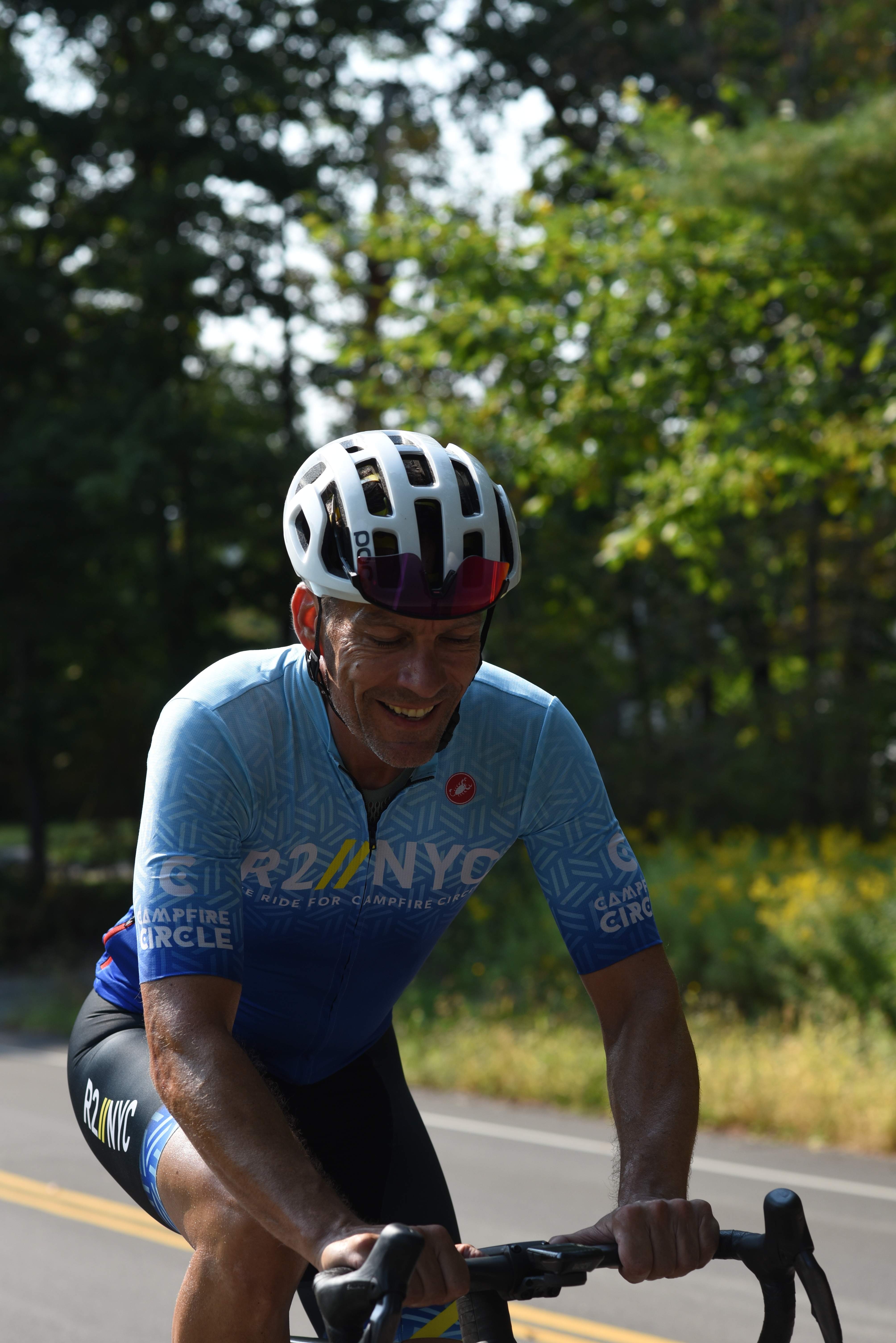 cyclist riding on a sunny day, surrounded by trees