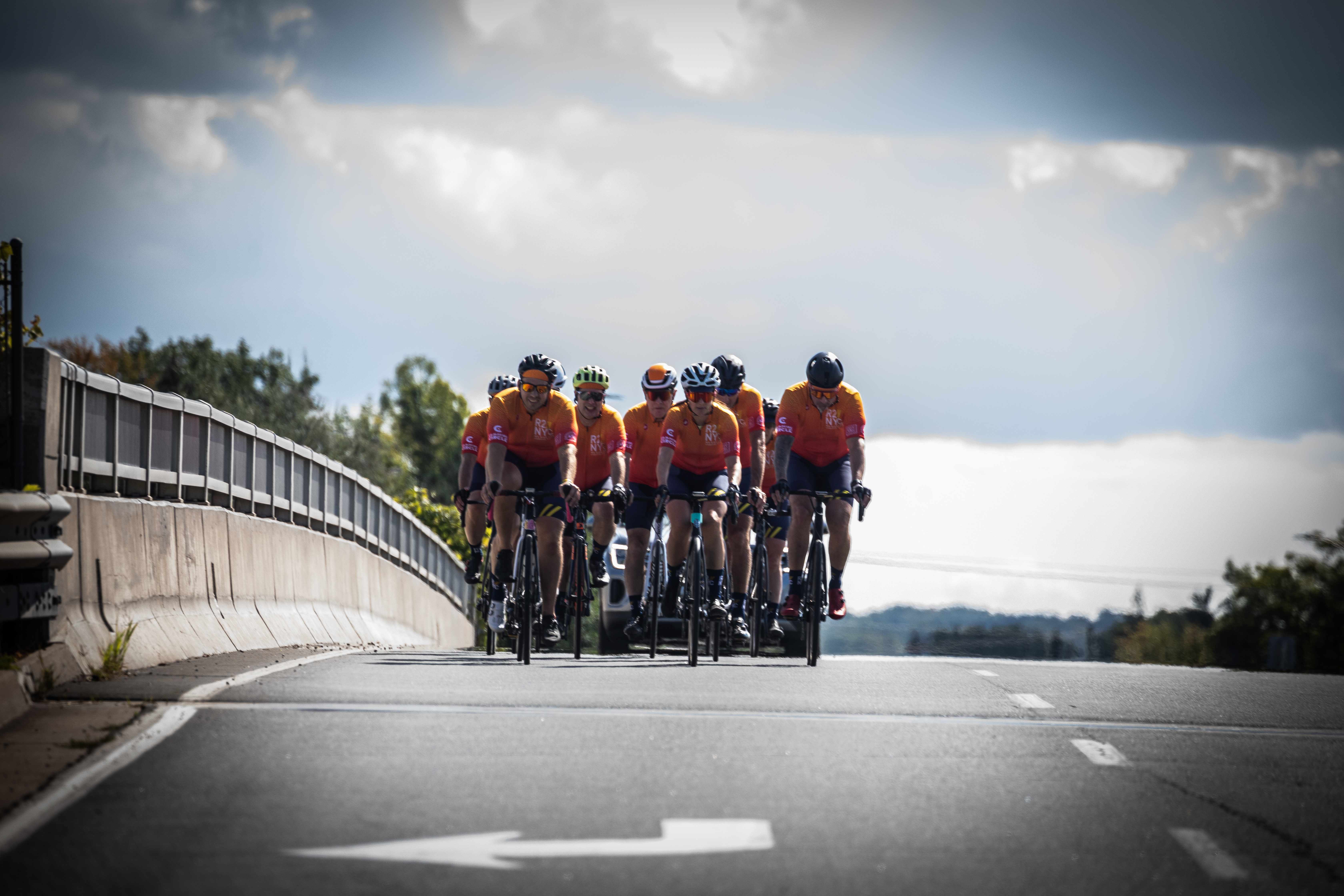 group of riders on the road with clouds behind them