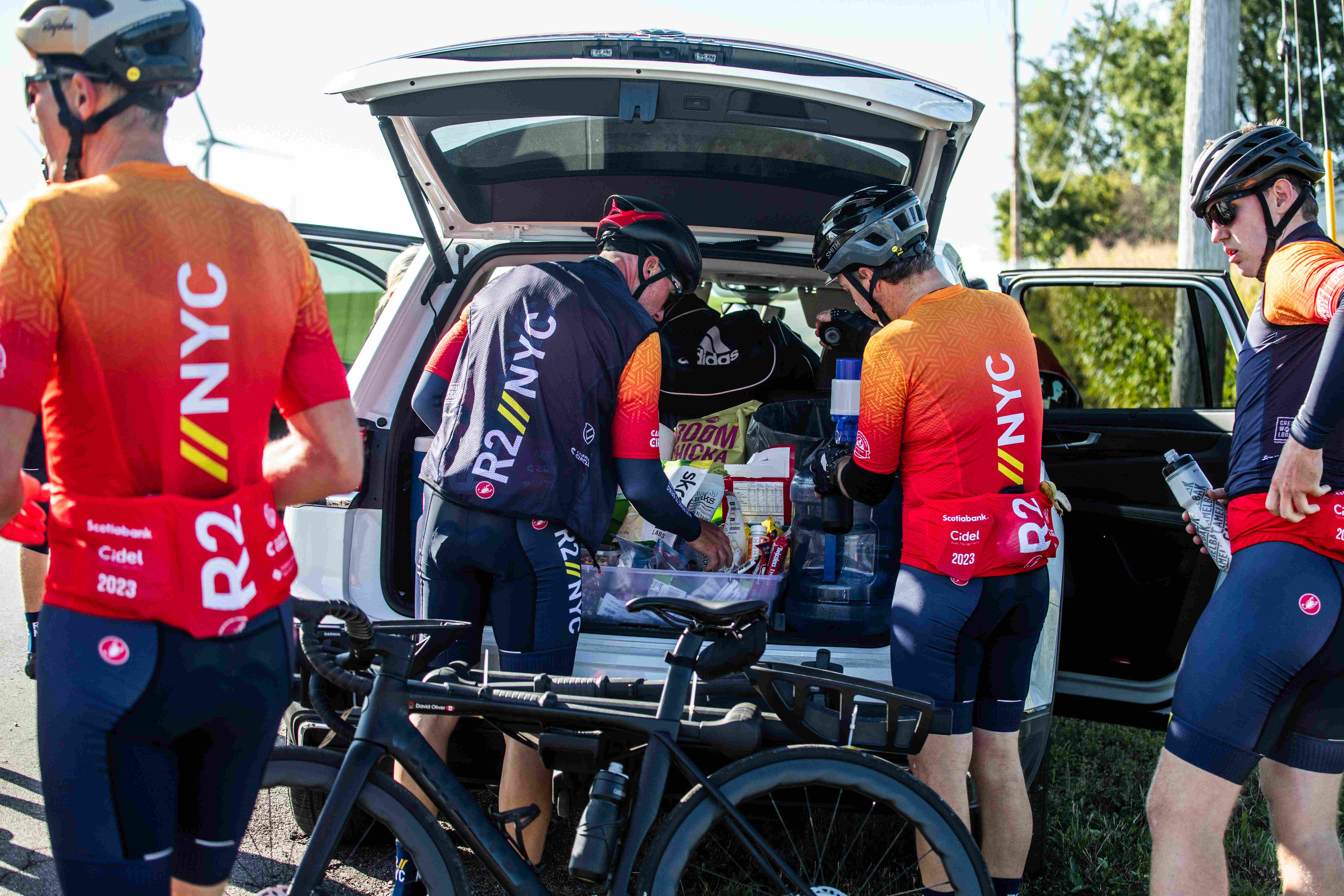 cyclists stopped for a break at trunk of support vehicle