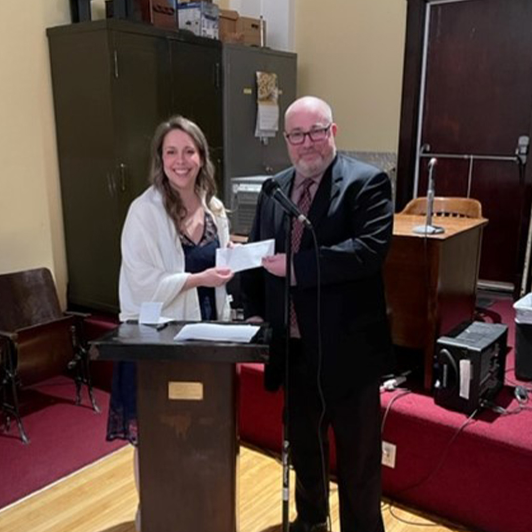 two people standing together for a picture holding a cheque