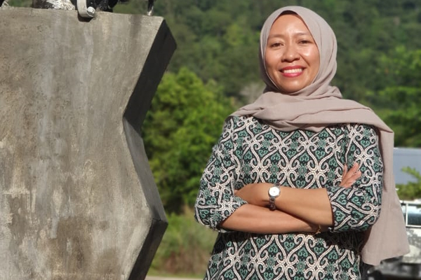 Nur Febriani Wardi smiling at the camera while posing beside chainsaw monument