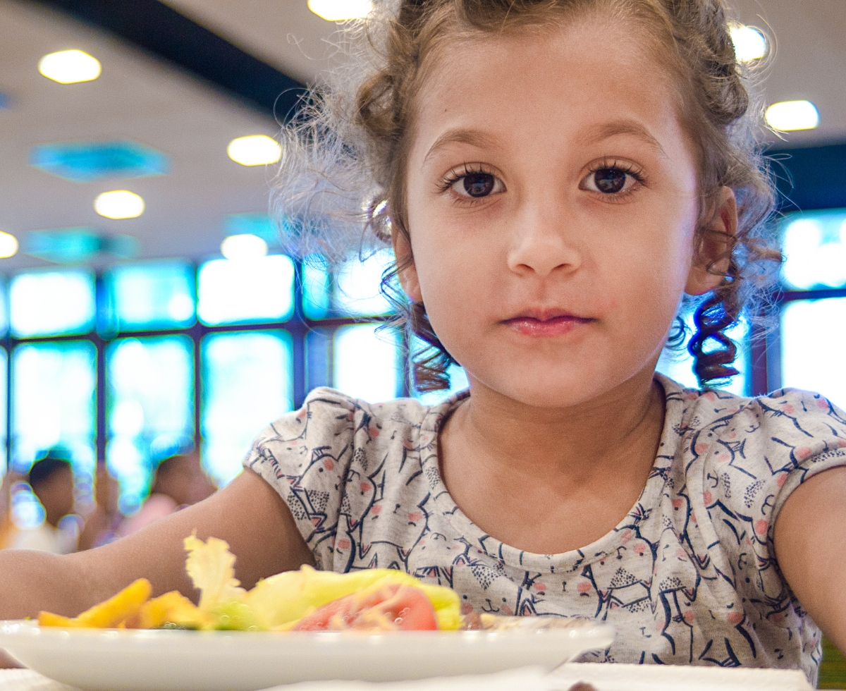 A girl looking at the camera with food in plate