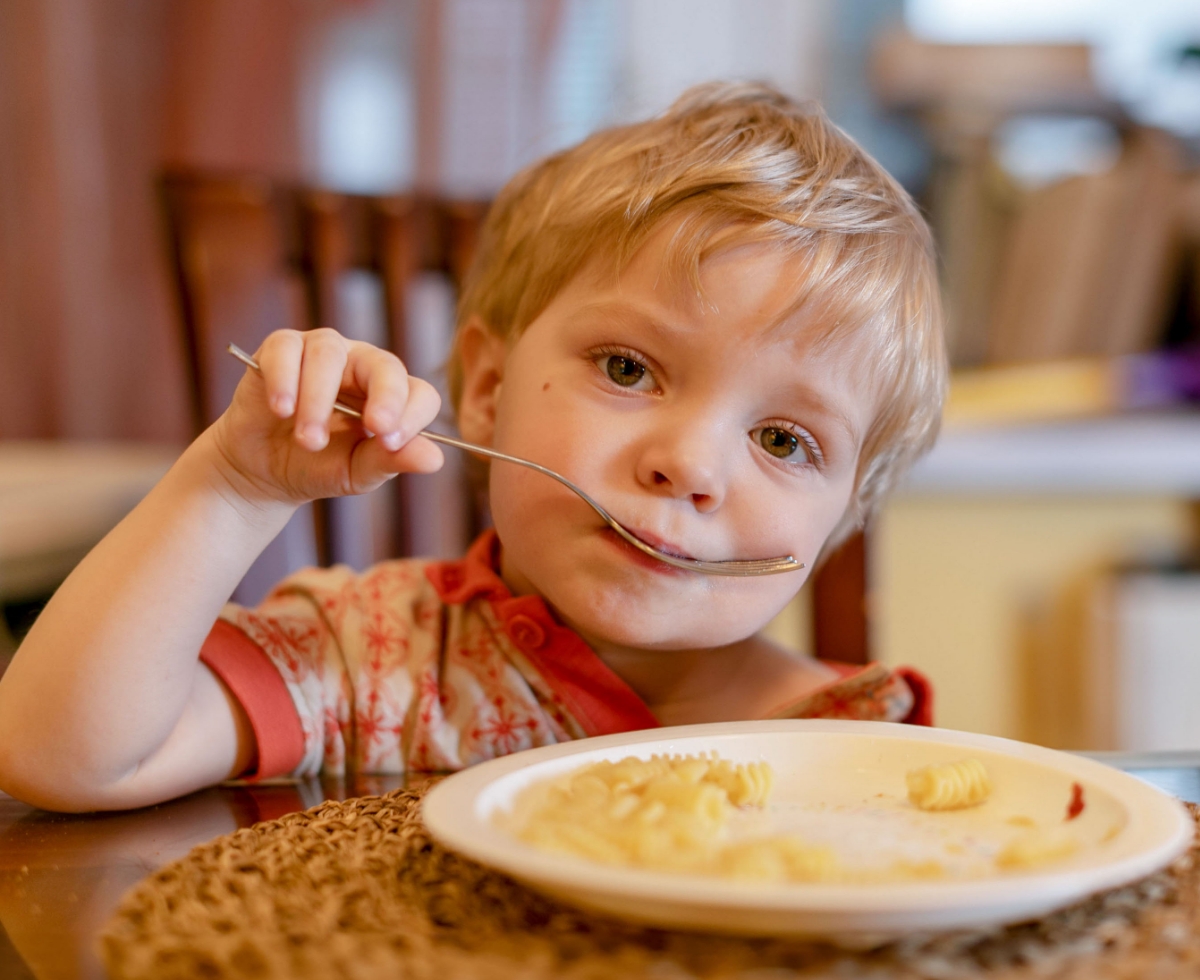 A child looking into camera with spoon in hand