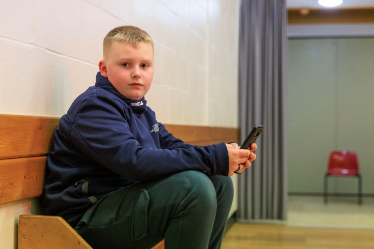 A boy sits holding his mobile