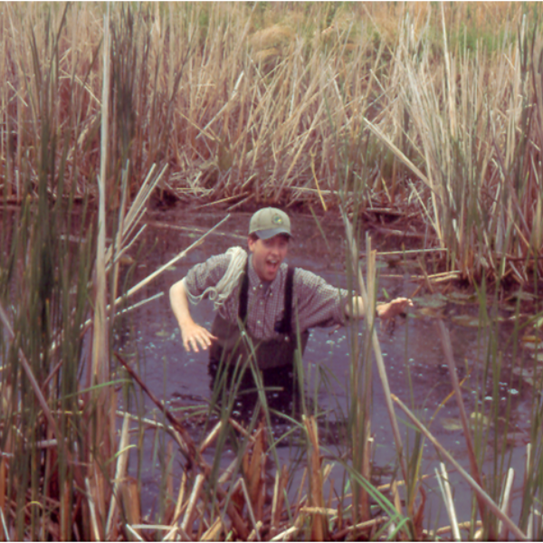 Doug Tozer is pictured wading in waist-high marsh water.