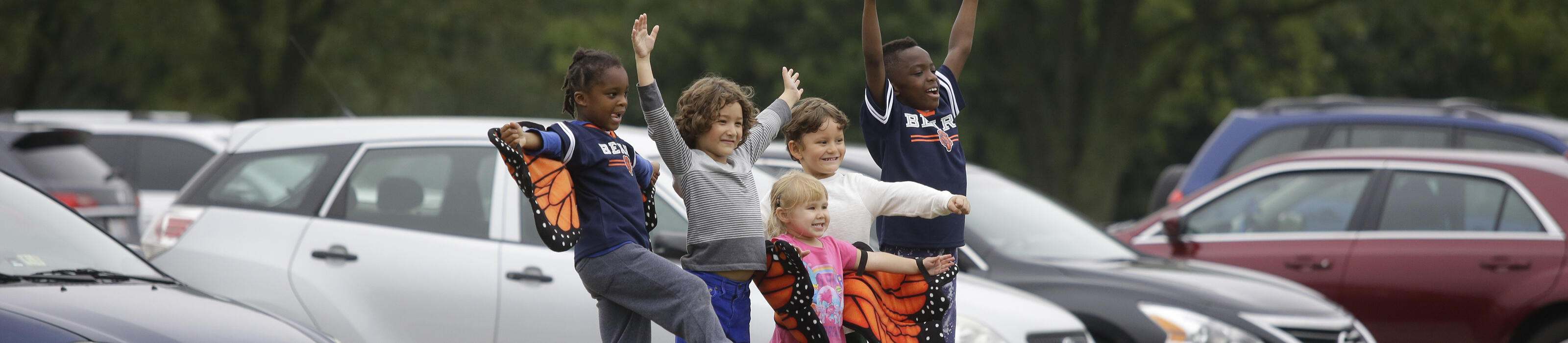 Five children stand on a picnic table with their arms outstretched as they rejoice at the Awe of Nature Festival. © Joshua Lott