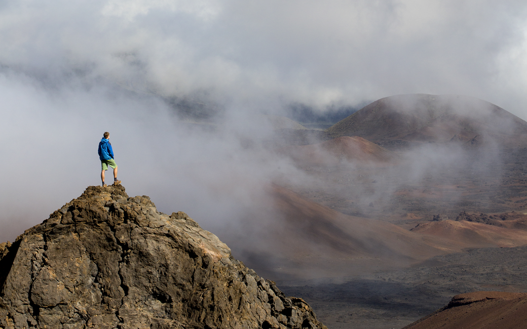 Person stands on a rock inside the creater of Haleakala National Park, Maui, Hawaii.