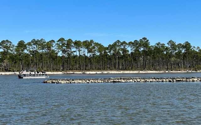 People look out over oyster reefs in Pensacola East Bay from a pontoon boat with shore in background. Photo credit: © Elaine Liles/TNC 