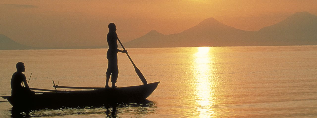 Locals in canoe at sunset in Kimbe Bay, Papua New Guinea. &copy; Chris Crowley