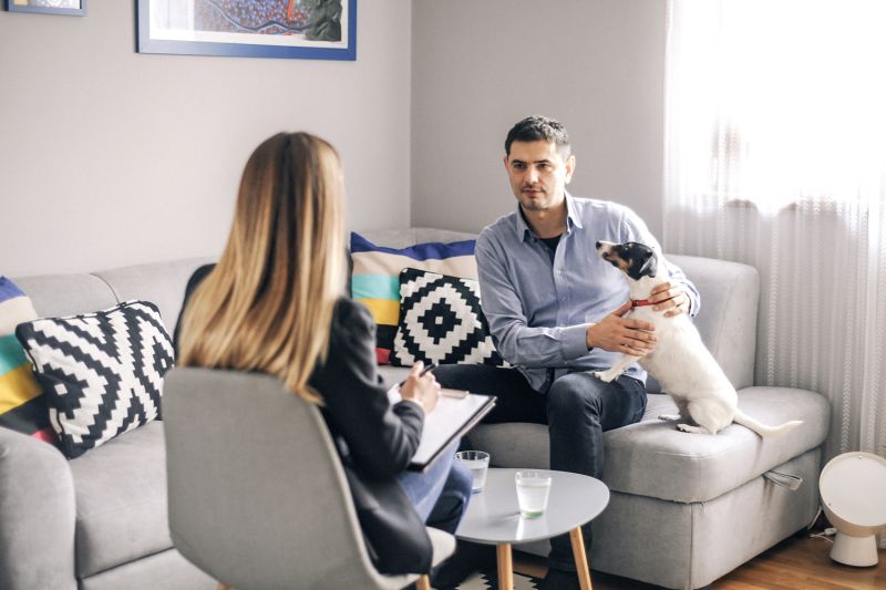 a woman speaks with a man holding a dog