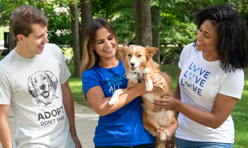 Three smiling people standing together in HSUS shirts with one holding happy dog