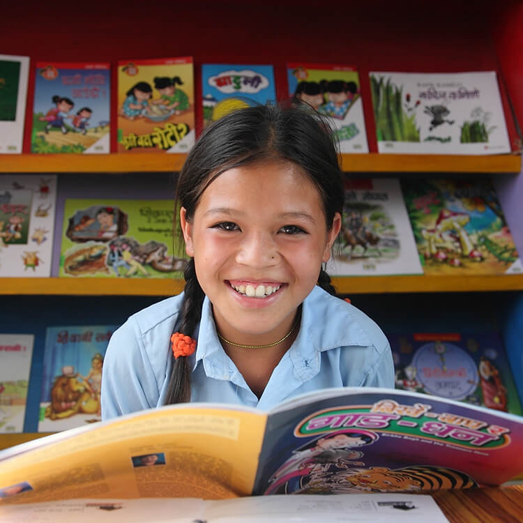 Photo of smiling school girl reading a book in a library
