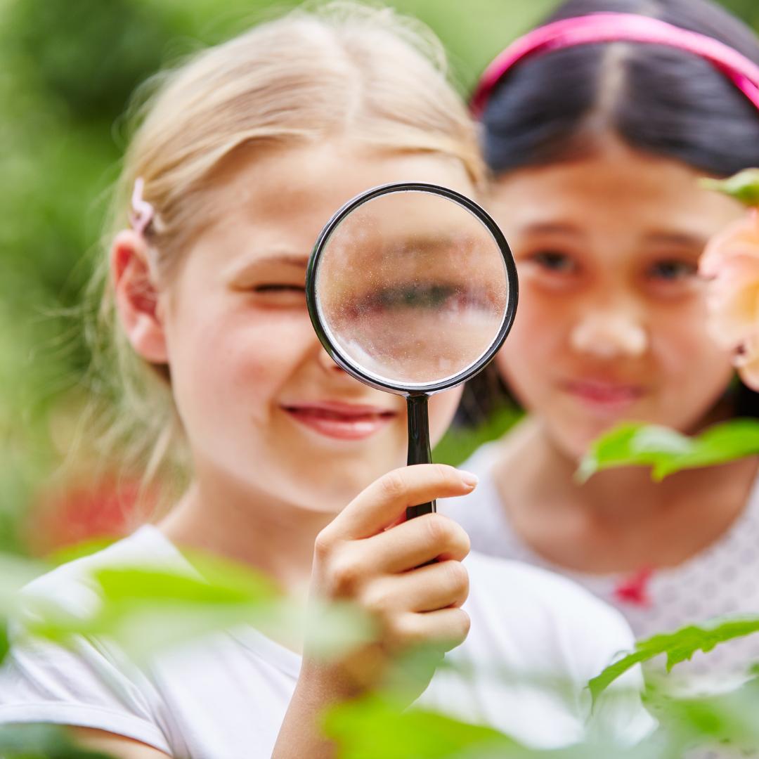This is a photo of two children looking through a magnifying glass