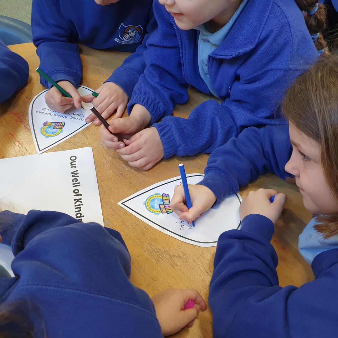 This is an image of children writing on their waterdrop for their well of kindness
